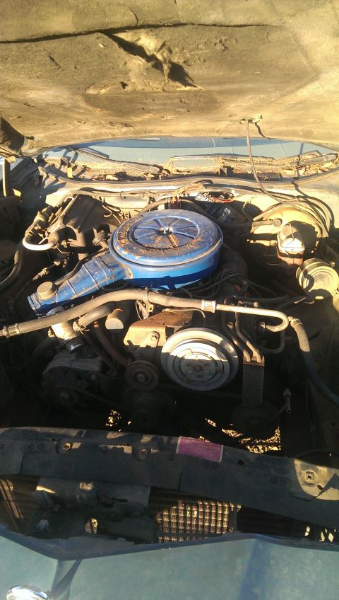 1975 Ford Ranchero - The engine bay of a vehicle is shown with the hood open, revealing the motor and its components.