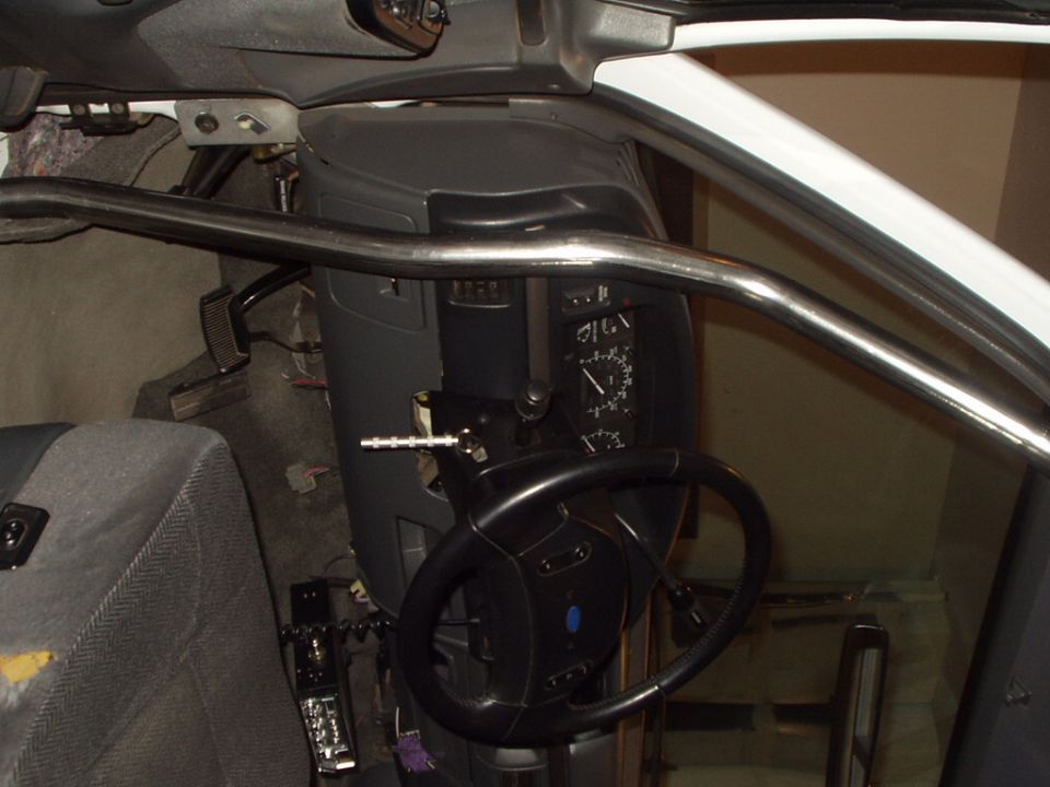 Vehicle interior with exposed steering column, roll bar tube, gauges and pedals during a build