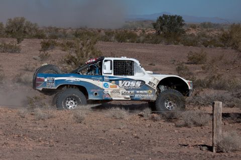 1996 Ford Bronco - A custom-built off-road truck competes in a desert race, dust billowing behind it.