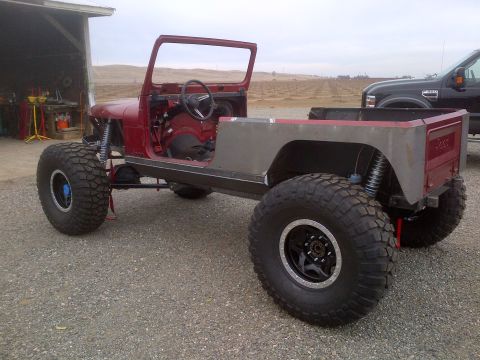 1985 Jeep CJ7 - This heavily modified Jeep is missing its doors, roof, and fenders, sitting on massive tires.