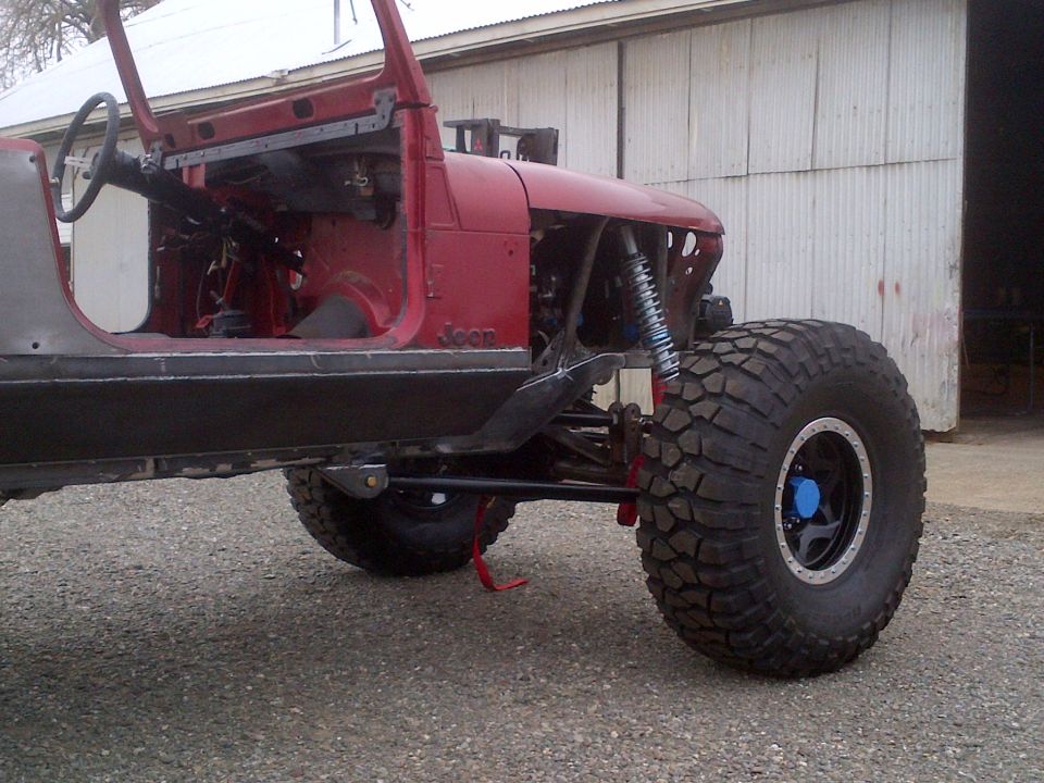 1985 Jeep CJ7 body with custom suspension and large off-road tires, partially disassembled