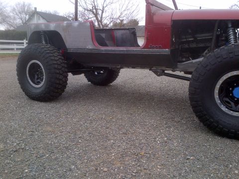 1985 Jeep CJ7 - Side view of a 1985 Jeep CJ7 body undergoing modification, fitted with oversized tires.