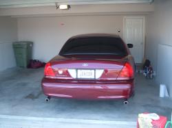 2004 Ford Crown Victoria - Rear view of a maroon Ford Crown Victoria parked in a garage with a trash can and other items visible.