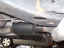 2004 Ford Crown Victoria - Close-up of a vehicle's undercarriage, focusing on the exhaust system and a rear wheel.
