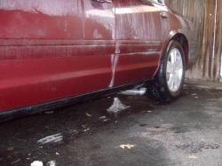 2004 Ford Crown Victoria - A red sedan is being washed, with soap suds covering its side and wheel.