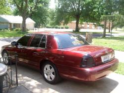 2004 Ford Crown Victoria - Rear three-quarter view of a red 2004 Ford Crown Victoria sedan with tinted windows.