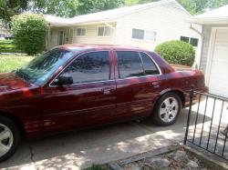 2004 Ford Crown Victoria - A maroon sedan is parked in a suburban driveway on a sunny day.