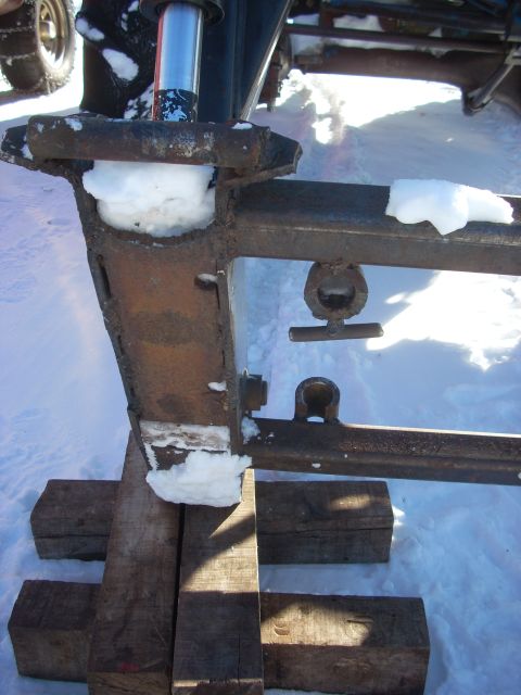 1963 Hummer H3 - The vehicle's frame is partially covered in snow, suggesting it's winter. The frame is supported by wooden blocks.