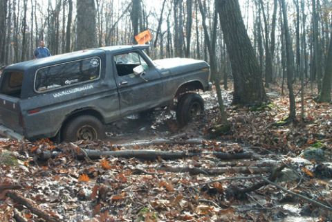 1979 Ford Bronco - Ford Bronco tackles a challenging muddy off-road course in a wooded area.