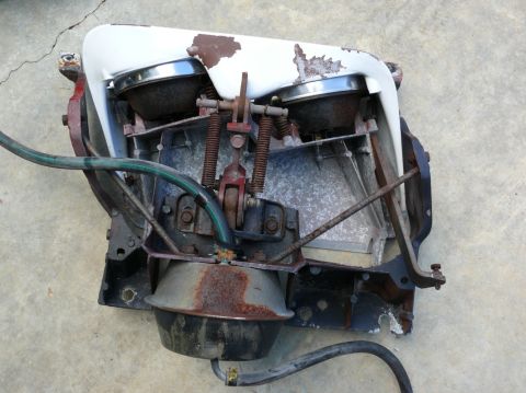 1976 Chevrolet Corvette - This is a close-up view of a car's headlight assembly, showing its internal mechanical components and weathered exterior.