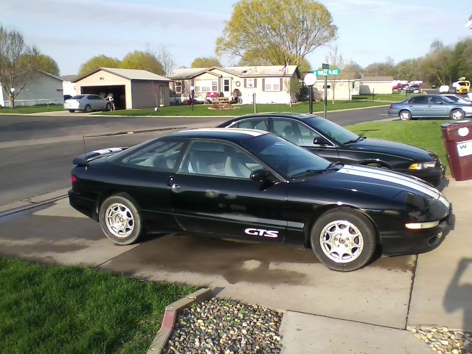 Black 1997 Ford Probe with white racing stripes parked on a driveway, side view