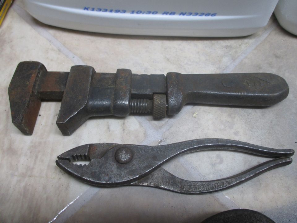 Adjustable wrench and pliers on a tiled surface