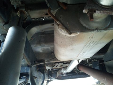 2003 Nissan Frontier - The underside of a vehicle reveals its exhaust system and suspension, with visible signs of age and use.