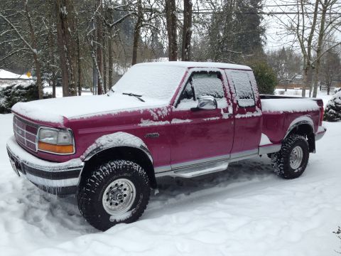 1992 Ford F-150 - A purple Ford F-150 pickup truck sits parked in the snow during winter.