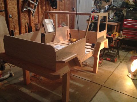 2005 Jeep Wrangler - A partially constructed wooden body of a vehicle sits on sawhorses in a workshop setting.