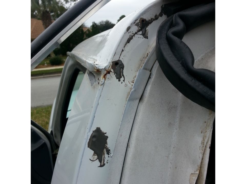 Close-up of rusted drip rail and surrounding body panel on a white vehicle