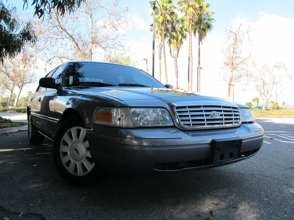 Gray 2006 Ford Crown Victoria parked outside with palm trees in the background