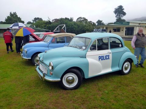 1969 MINI Cooper - A classic Morris Minor police car is displayed on a grassy field alongside other vintage vehicles.