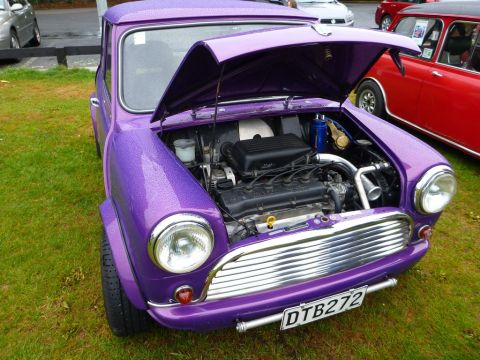 1969 MINI Cooper - Purple 1969 MINI Cooper on display with its engine exposed, parked next to another classic car.