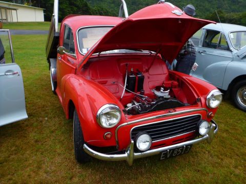 1969 MINI Cooper - Red pickup truck with its hood open, parked on grass next to another vehicle.