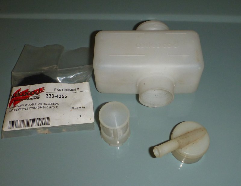 Brake fluid reservoir, cap, and a small plastic piece, with a Wilwood Engineering part number label