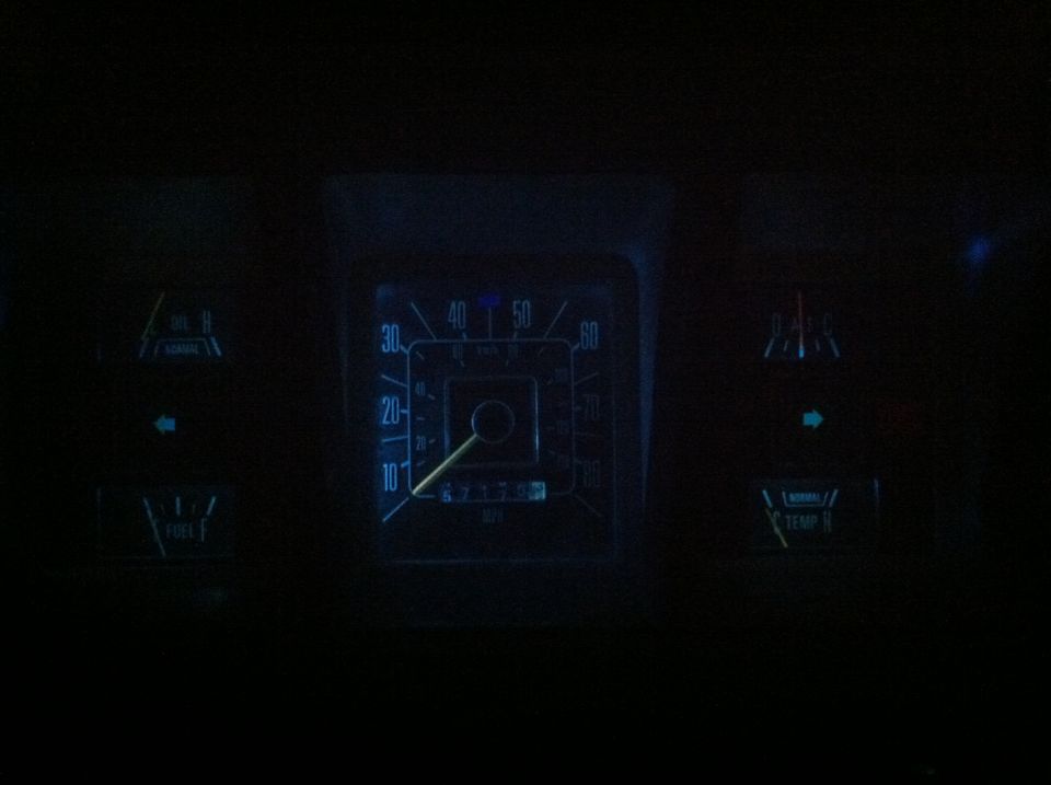 Dark dashboard with illuminated gauges: speedometer, fuel, temperature, and indicator lights