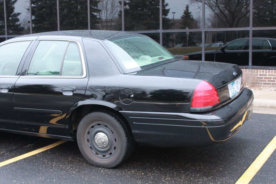 Black sedan parked in a lot, reflection of another car in the window