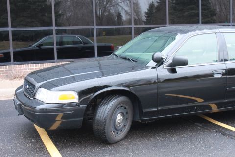 2005 Ford Crown Victoria - A black sedan is parked outside a building with a reflection of another car visible in the windows.