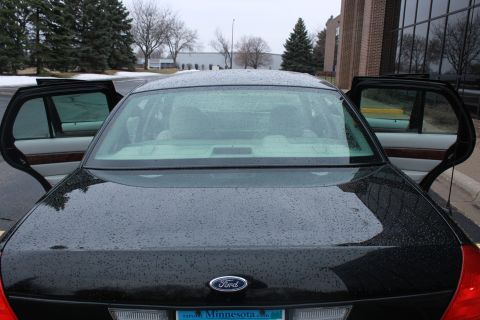 2005 Ford Crown Victoria - Rear view of a black 2005 Ford Crown Victoria, showing the Ford badge and open doors.