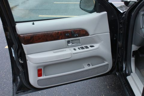 2005 Ford Crown Victoria - Interior view of a car's front door panel, showing the door handle, window controls, and storage pocket.