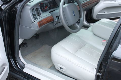 2005 Ford Crown Victoria - The interior of a 2005 Ford Crown Victoria, light-colored leather seats and wood trim accents on the dashboard.