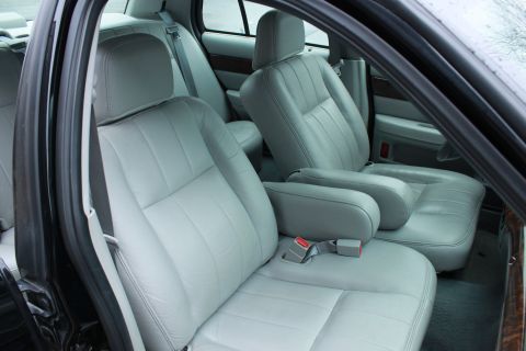 2005 Ford Crown Victoria - The interior of a car features light gray leather seats and wood trim accents.