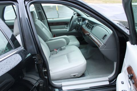 2005 Ford Crown Victoria - Interior view of a black car, showing the front seats and dashboard with wood accents.