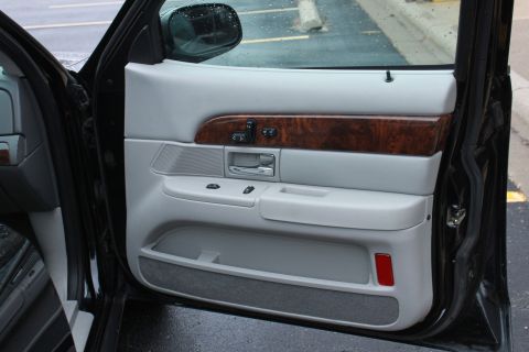 2005 Ford Crown Victoria - Close-up view of the interior door panel, wood trim and gray upholstery.
