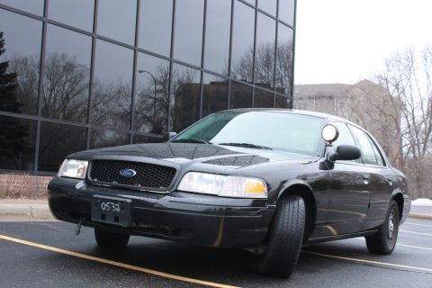 2005 Ford Crown Victoria - A black Ford Crown Victoria is parked in front of a building with reflective windows.