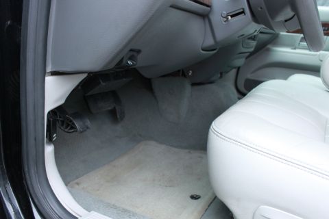 2005 Ford Crown Victoria - Interior view of the driver's side footwell and white leather seat in a 2005 Ford Crown Victoria.