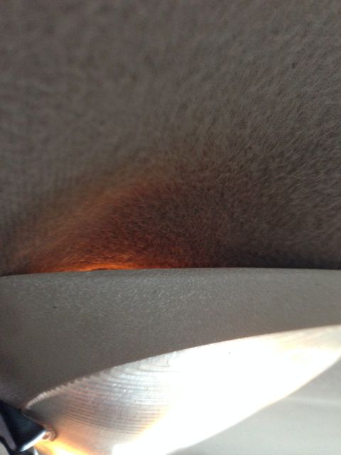 1996 Ford Bronco - Interior view of a car's ceiling and dashboard trim, with a subtle orange light reflection.
