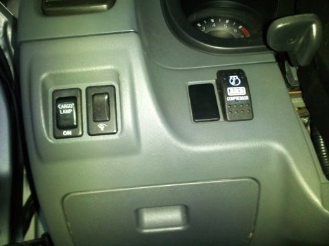2003 Nissan Frontier - Interior view of a vehicle's dashboard, showing various control switches and part of the instrument cluster.