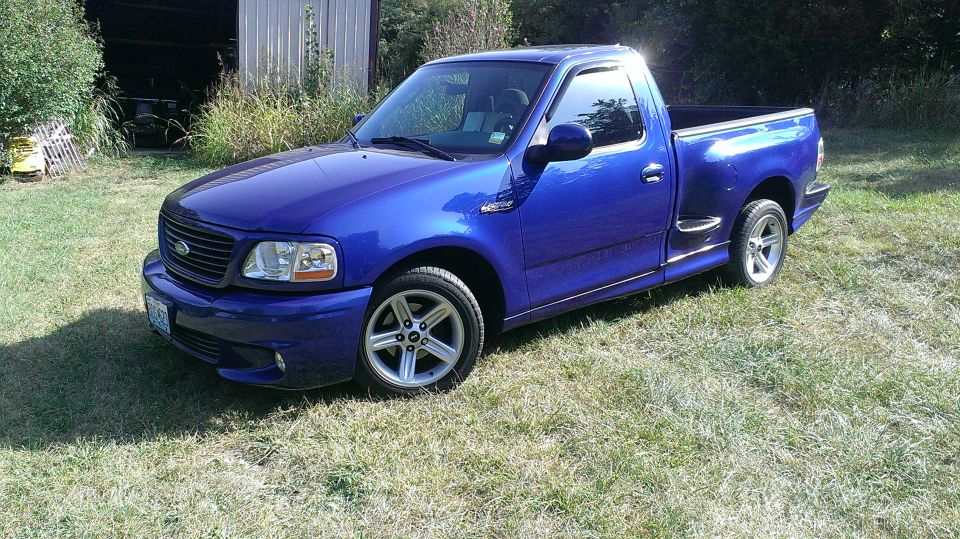 Blue 2003 Ford F-150 Lightning pickup truck parked on grass