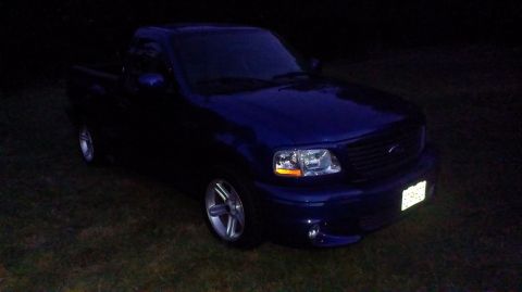 2003 Ford F-150 - A blue 2003 Ford F-150 is parked outside at night, with its headlights on.