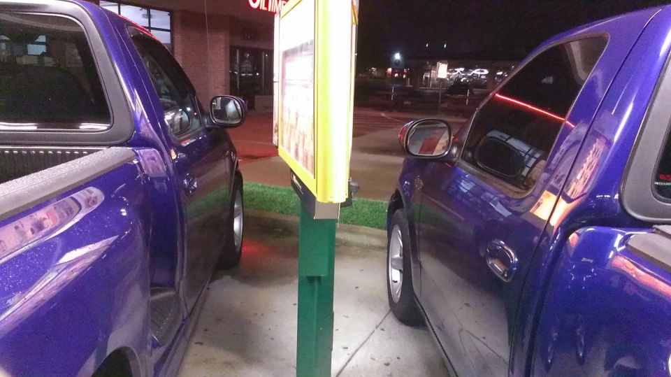 Two purple Ford F-150 trucks parked side-by-side at a drive-thru menu