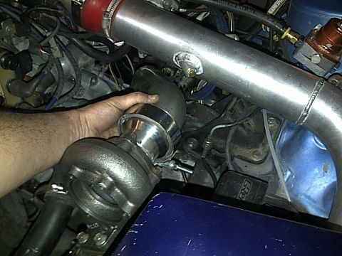1995 Ford Probe - Close-up of a hand installing a turbocharger into an engine bay, with visible piping and wiring.
