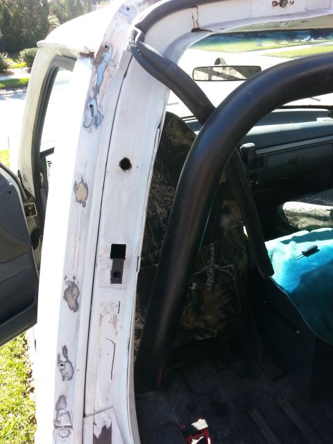 1992 Ford Bronco - The interior of a white vehicle reveals a roll cage and evidence of bodywork on the door frame.