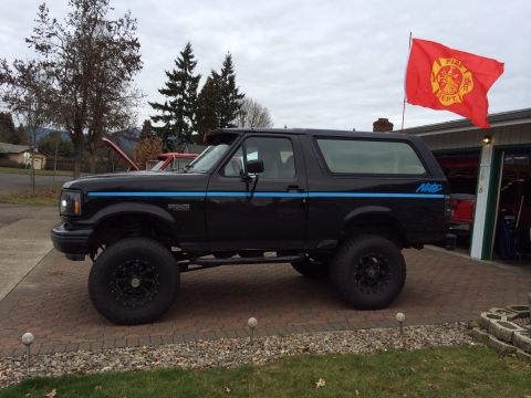 1992 Ford Bronco - This lifted black Ford Bronco features a distinctive blue stripe and a 'Nite' decal on the rear quarter panel.