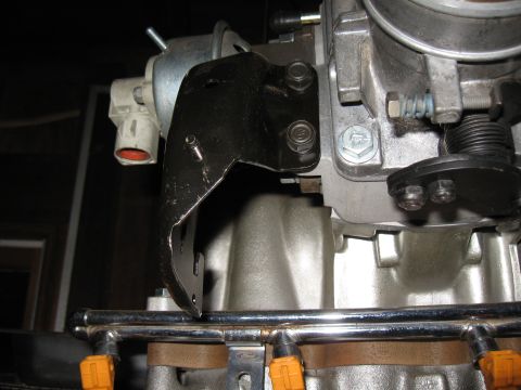 1994 Ford Bronco - A metal bracket is bolted to an engine component, with visible fuel injectors and throttle body.