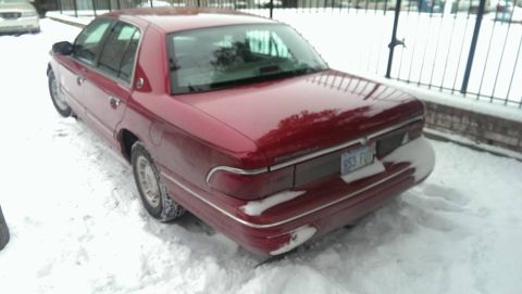 2000 Mercury Grand Marquis - A red Mercury Grand Marquis is parked in the snow, showing its rear end and license plate.