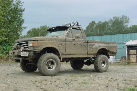 1990 Ford F-150 - This heavily modified 1990 Ford F-150 pickup truck is covered in mud, indicating off-road use.