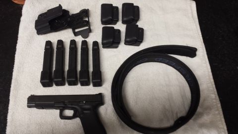 1996 Ford Bronco - A black handgun is laid out with its accessories, including magazines, a holster, and belt loops, on a white cloth.