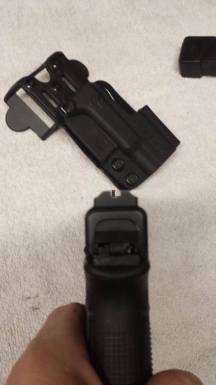 1996 Ford Bronco - A black pistol and holster are displayed on a towel. The image includes a watermark for SUPERMOTORS.
