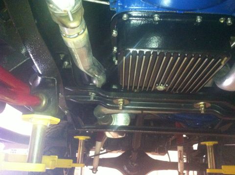 1982 Ford Bronco - Close-up of the engine oil pan and exhaust system from underneath a vehicle.